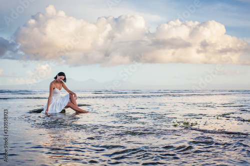 Beautiful woman by the ocean at sunset