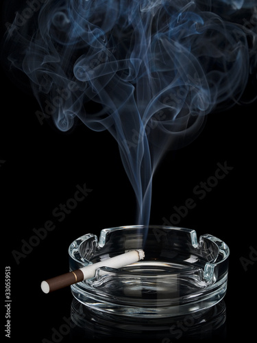 Curling smoke from one cigarette in an ashtray