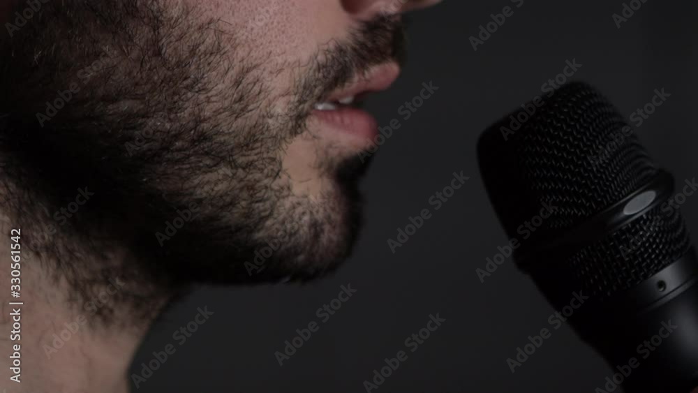 Young bearded Man talks to microphone. Man microphone speech, close up side view