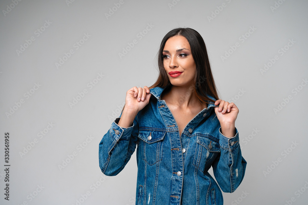 Beautiful caucasian girl in a denim jacket posing in the studio on a white background.