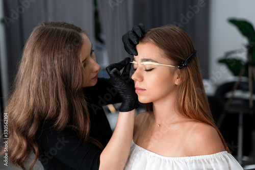 Young beautician caucasian girl holds model eyebrow correction