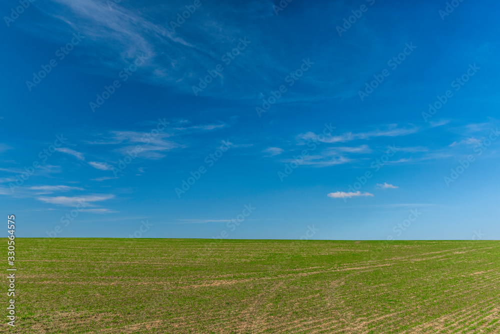 Blue sky with white clouds and green field