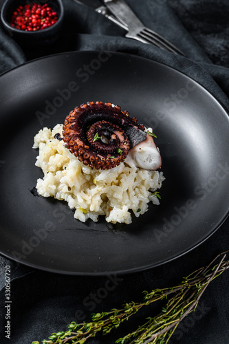 A portion of Risotto with octopus tentacles. Black background. Top view