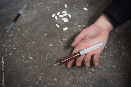 Hand of the narcotist with syringe on the floor. The concept of drug abuse, overdose. photo