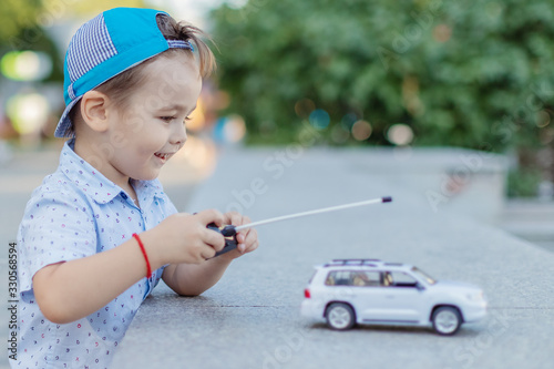 a small boy plays with a toy car on radio control holding a remote control photo