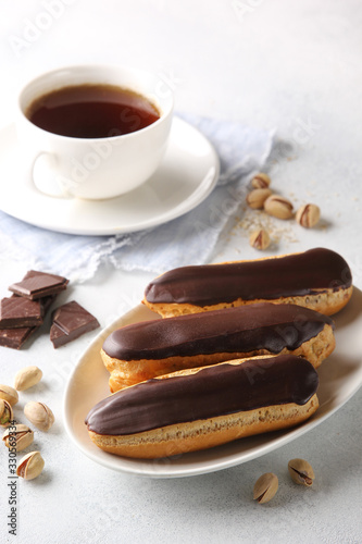 Dessert. Eclairs with chocolate glaze with a cup of coffee. Cake with cream. Chocolate, pistachios on a light background. Background image, copy space