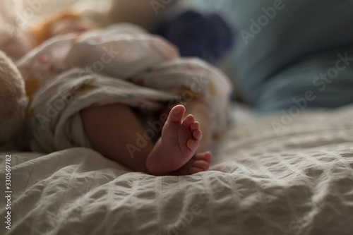A newborn baby`s tiny feet sticking out from a swaddled blanket.