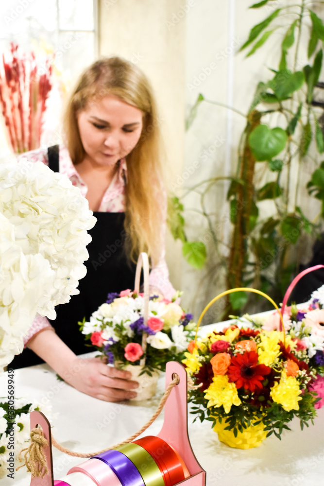 A woman makes fresh bouquet. Florist collects floral arrangement. The seller in flower shop.