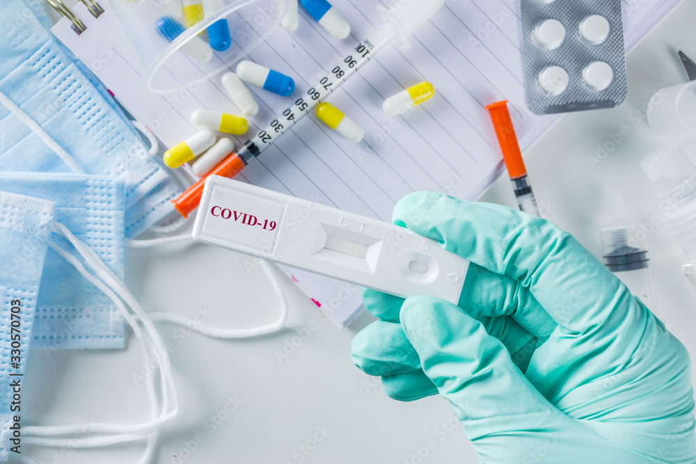 Fototapeta premium Worldwide coronavirus epidemic concept. Pandemic COVID-19, 2019-nCoV. Laboratory test strip for antibody or sars-cov-2 virus disease. In doctor hands. With pills, vaccination syringes, notebook.