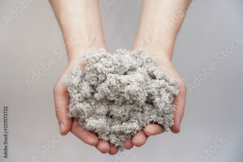 Hands holding cellulose fiber for ecological insulation of the house. Conservation of home heat and energy saving