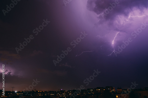 City view at night under thunderstorm with strike of lightning. Bad weather. 