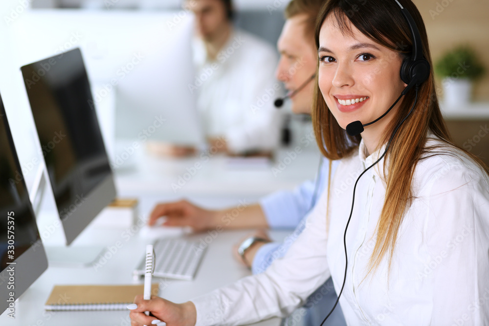 Call center. Group of diverse operators at work. Focus on beautiful asian woman in headset at customer service office. Business concept Call center. Group of diverse operators at work. Focus on beautiful asian woman in headset at customer service office. Business concept