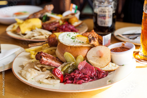 Beer set with appetizers, fried sausage, crackers, chips, chicken legs, pork, ribs, potatoes, fried eggs, pickles, sauce on a table in a beer restaurant