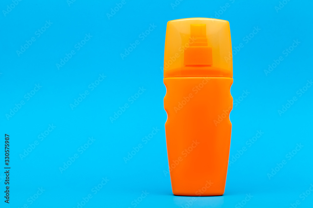 orange unlable bottle of sunscreen on a blue background with copy space. orange unlable bottle of sunscreen on a blue background with copy space.
