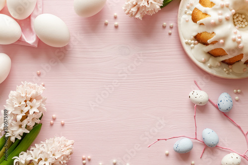 Easter pastel pink background with fresh hyacinths, iced cake and eggs with copy space, top view