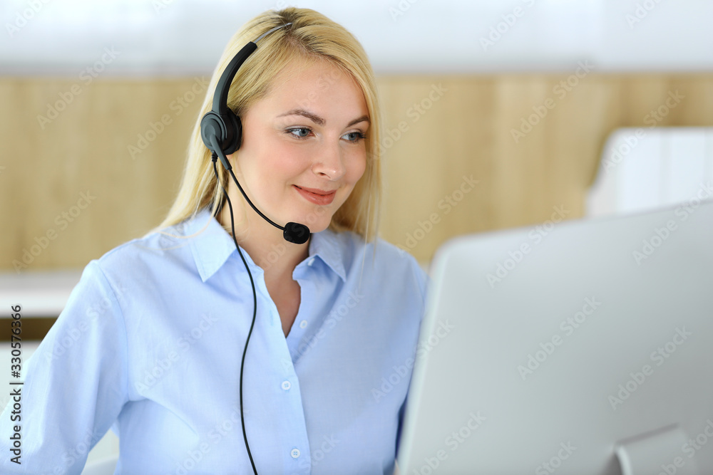 Call center. Blonde business woman sitting in headset at customer service office. Concept of telesales business or home office occupation Call center. Blonde business woman sitting in headset at customer service office. Concept of telesales business or home office occupation