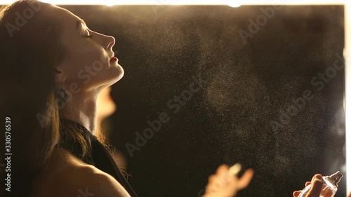 A young woman is applying perfume.