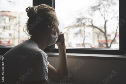 woman with protection medical face mask by the window photo