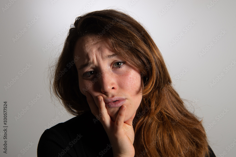 Portrait of sad brunette girl looking at camera over white background. Frowning young woman leaning face on her hand. Emotions in female face... Portrait of sad brunette girl looking at camera over white background. Frowning young woman leaning face on her hand. Emotions in female face...
