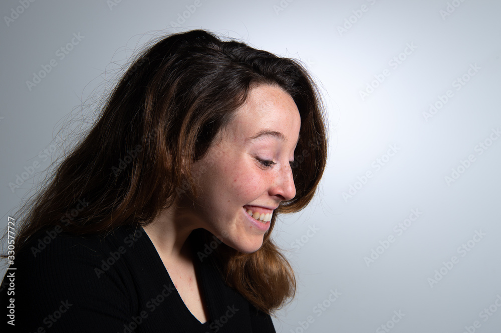 Side view of smiling attractive young brunette woman looking to the side over white background. Emotions in female face... Side view of smiling attractive young brunette woman looking to the side over white background. Emotions in female face...