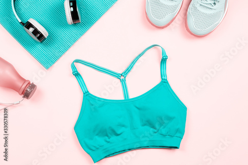 Woman fitness clothes and accessories flat lay on pink, copy space. Sport fashion for women with sport bra, yoga leggins, headphones, yoga mat. Healthy lifestyle concept photo