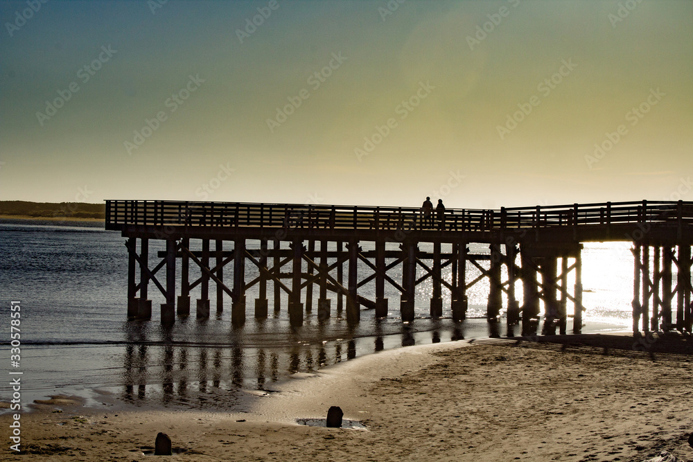 Couple Silhouetted on a Wooden Pier at the Beach during sunset