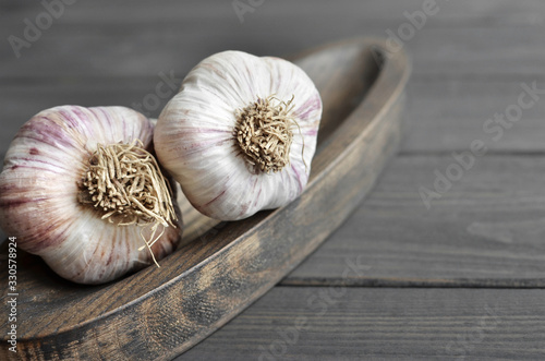 Dry fresh organic garlic bulbs on wooden plate over dark wooden background