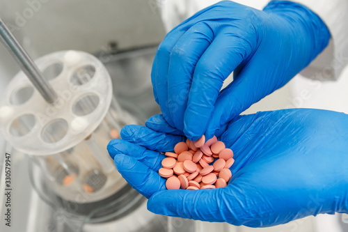 Pharmacist in medical gloves testing new medicine pills in a pharmaceutical laboratory.