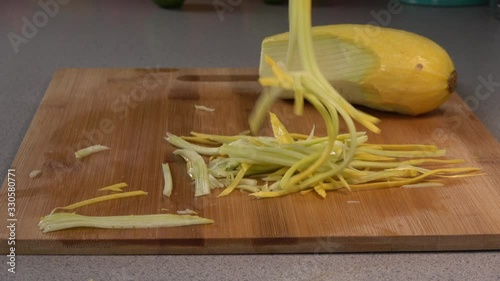  Original name(s): Dropping julienned slices of yellow summer squash on a wood cutting board. photo