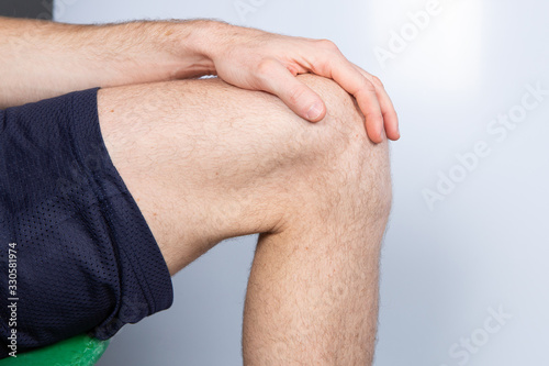 Caucasian male leg bent in knee. Hand laying on leg. White background...