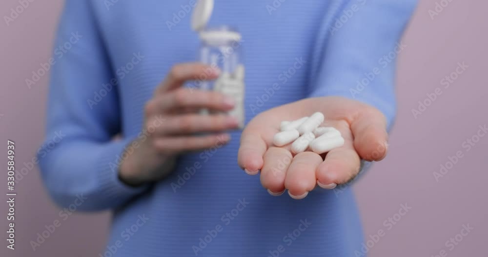 Woman's hand holds white tablets in gel shell in palm outstretched to camera on pink background. Health, complex of vitamins for people. Health care. Taking medication, pills. Lifestyle Woman's hand holds white tablets in gel shell in palm outstretched to camera on pink background. Health, complex of vitamins for people. Health care. Taking medication, pills. Lifestyle