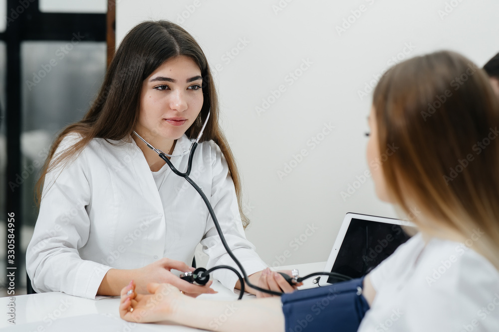 The doctor measures the pressure of a pregnant girl in the clinic. Pregnancy, and health care The doctor measures the pressure of a pregnant girl in the clinic. Pregnancy, and health care