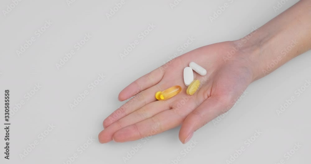 Woman's hand clenched into fist unclenches palm pills, capsules gel shell diagonal white background. Omega 3, Multivitamins, Calcium, Antibiotics. Health, complex vitamins. Health care. Medication Woman's hand clenched into fist unclenches palm pills, capsules gel shell diagonal white background. Omega 3, Multivitamins, Calcium, Antibiotics. Health, complex vitamins. Health care. Medication