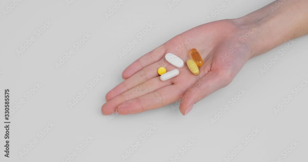 Woman's hand clenched into fist unclenches palm pills, capsules gel shell diagonal white background. Omega 3, Multivitamins, Calcium, Antibiotics. Health, complex vitamins. Health care. Medication Woman's hand clenched into fist unclenches palm pills, capsules gel shell diagonal white background. Omega 3, Multivitamins, Calcium, Antibiotics. Health, complex vitamins. Health care. Medication