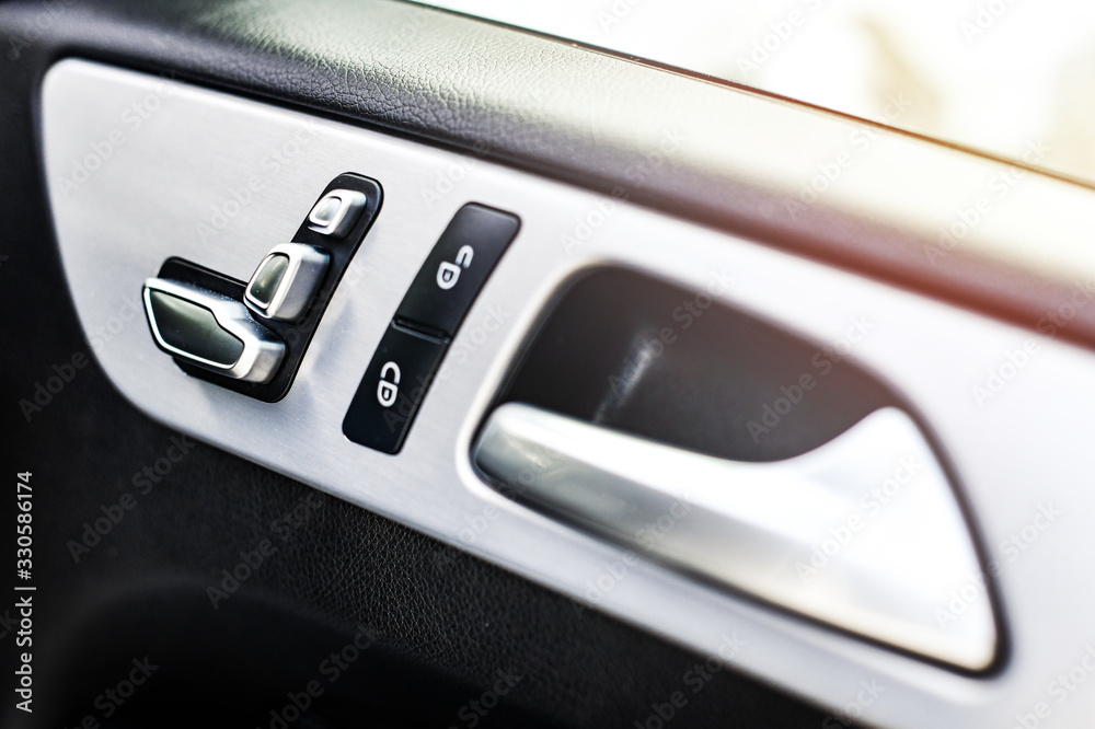 Car interior details of door handle with windows controls buttons and adjustments. Luxury close up or car window controls system.