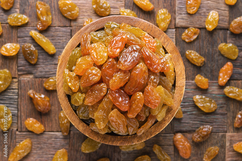 large, light raisins in wooden bowl, top view.