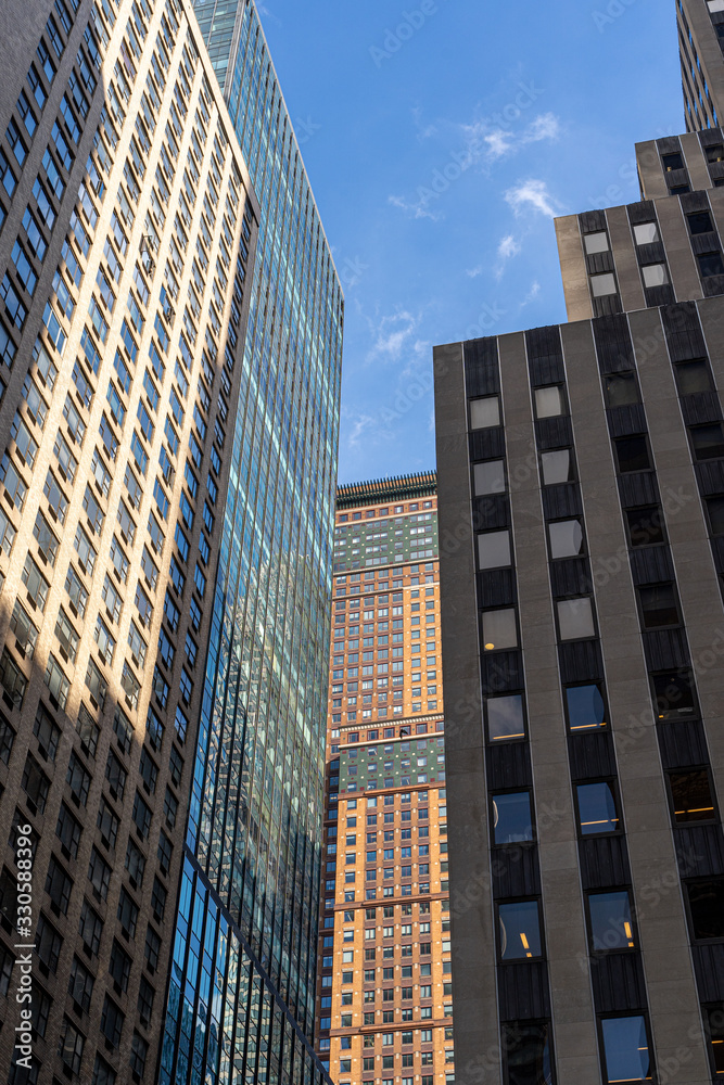Detail close up of a glass skyscraper in Manhattan, New York City, close tu sunset on a sunny day. Black blue yellow and orange hues Detail close up of a glass skyscraper in Manhattan, New York City, close tu sunset on a sunny day. Black blue yellow and orange hues