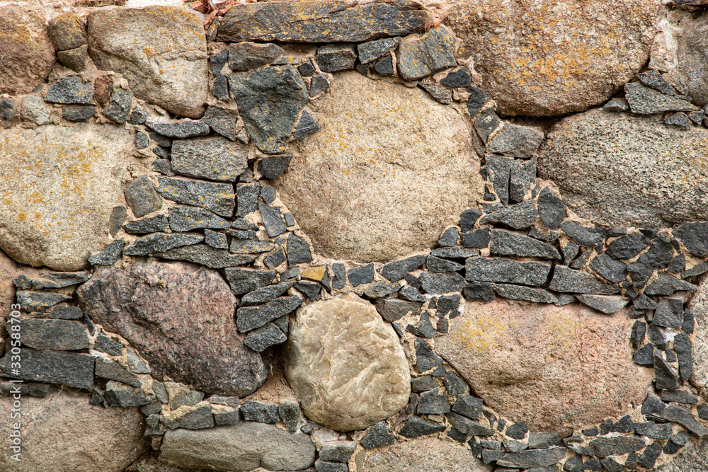 Fototapeta premium old masonry of small and large stones covered with lichen