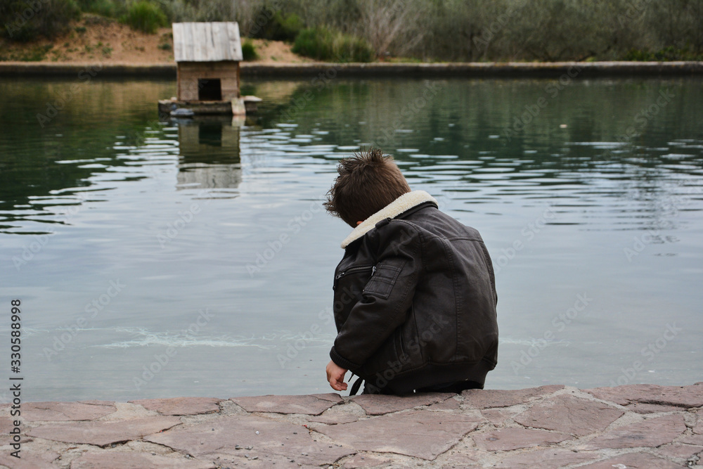 Dark boy watching the water raft with ducks, Dark boy watching the water raft with ducks,