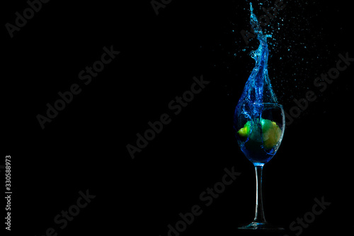 Lemon fell into a glass with blue water, a beautiful splash, cocktail on a black background