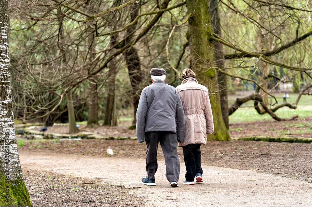 a pair of elderly people walking together outdoors a pair of elderly people walking together outdoors