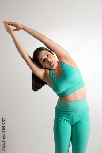 Pretty young woman performing stretching exercises in the gym