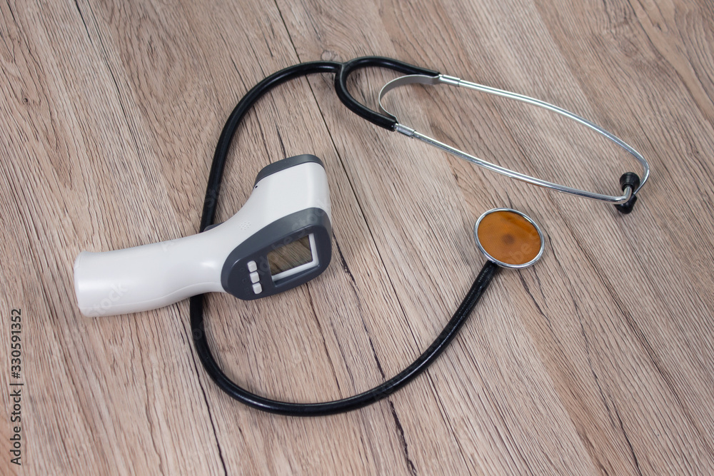 Termometr elektroniczny i stetoskop lekarski leży na stole. Przedmioty lekarskie pomagające w walce z epidemią wirusa.