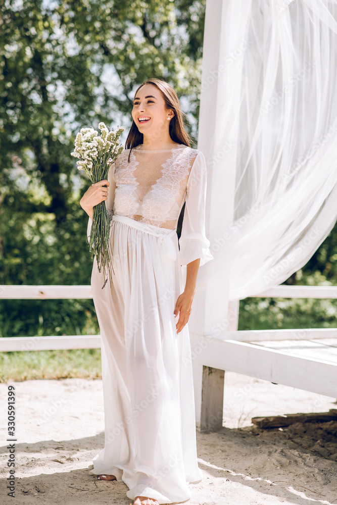 beautiful girl in a white dress and holds a bouquet of flowers beautiful girl in a white dress and holds a bouquet of flowers