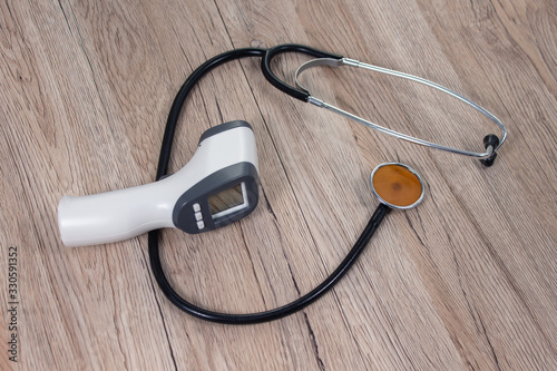Termometr elektroniczny i stetoskop lekarski leży na stole. Przedmioty lekarskie pomagające w walce z epidemią wirusa.