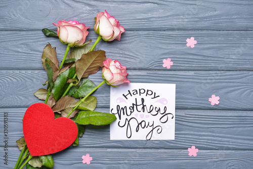 Beautiful greeting card and flowers for Mother's Day on wooden background