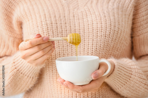 Woman drinking tea with honey, closeup