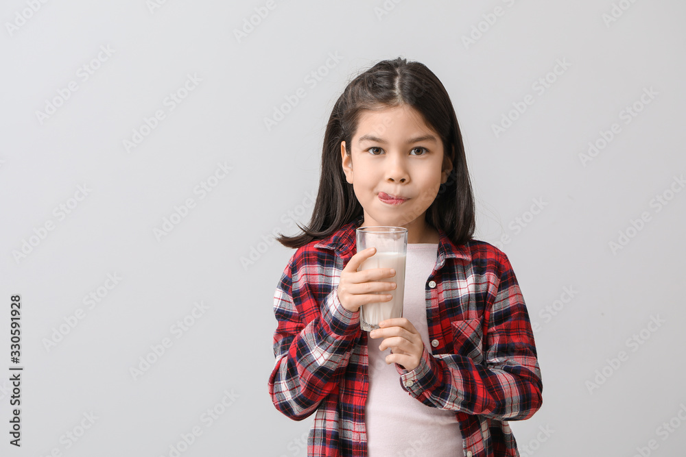 Cute Asian girl with milk on light background Cute Asian girl with milk on light background
