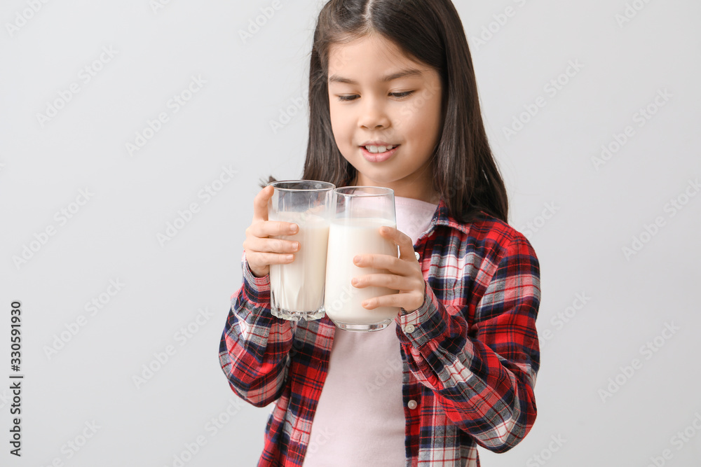 Cute Asian girl with milk on light background Cute Asian girl with milk on light background