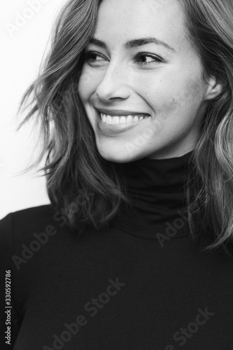 Portrait of young happy woman in black and white with a big smile on her face looking at one side